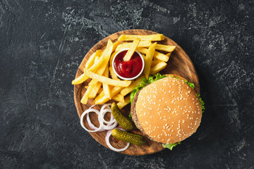 Burger, hamburger or cheeseburger served with french fries, pickles and onion on wooden board. Top...