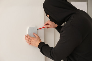 Male thief trying to break alarm system, indoors