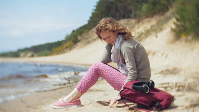 A woman listens to music on headphones, relaxes and dances on the shore of the sea river of the ocean. Technology in the open air