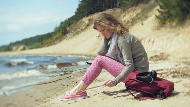A woman listens to music on headphones, relaxes and dances on the shore of the sea river of the ocean. Technology in the open air