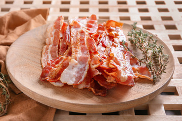 Tasty fried bacon with thyme on wooden board