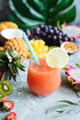 Tropical juice or cocktail in a glass with drinking straw. Closeup view, selective focus