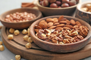 Different kinds of nuts in bowls on table, closeup
