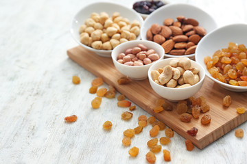Different kinds of nuts in bowls and raisins on table