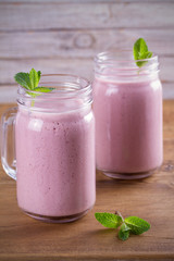 Two glasses of pink strawberry milkshake or cocktail. Strawberry banana smoothie on wooden table. vertical