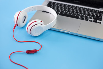 Obraz premium white headphones and laptop on blue background.