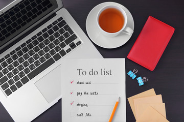 Composition with to-do list and laptop on dark table