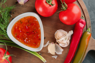 Bowl with tasty sauce and vegetables on wooden board