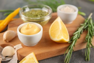 Bowls with different sauces on wooden board, closeup