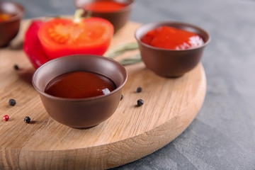 Bowls with different sauces on wooden board, closeup