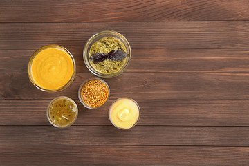 Bowls with different sauces on wooden background, top view