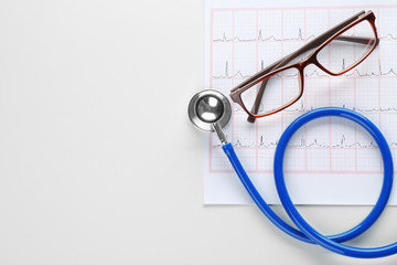 Cardiogram with stethoscope and eyeglasses on white background