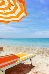 Beach equipment, chairs and sun umbrella on white sandy beach with light blue sea water, beach vacation concept © barmalini