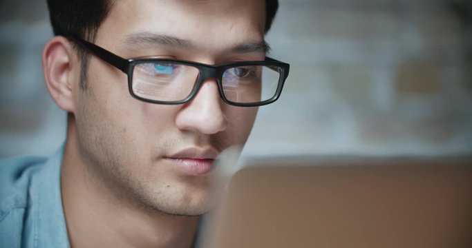 Young handsome asian businessman working at laptop in loft office dollyshot 4k