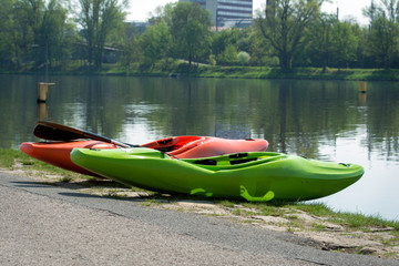 Red & green kayaks on the shore, next to the river. Prague, Vltava river.