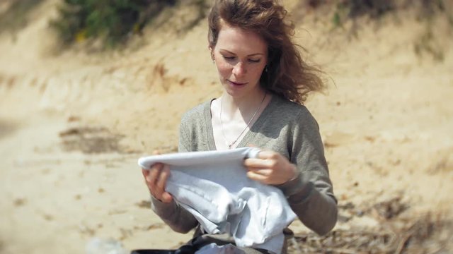 A woman listens to music on headphones, relaxes and dances on the shore of the sea river of the ocean. Technology in the open air