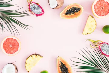 Foto op Plexiglas Zomer fruit. Tropische palmbladeren, ananas, kokosnoot, papaya, drakenfruit, sinaasappel op pastelroze achtergrond. Platliggend, bovenaanzicht, kopieerruimte © Flaffy