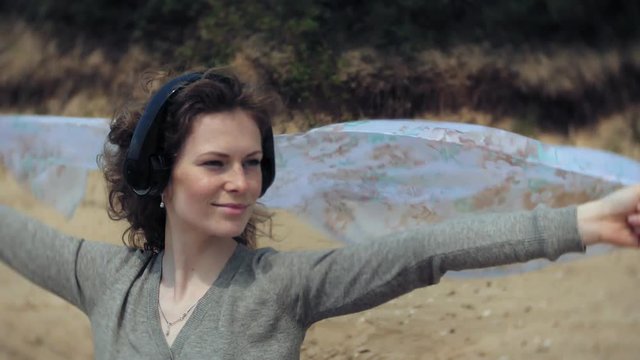 A woman listens to music on headphones, relaxes and dances on the shore of the sea river of the ocean. Technology in the open air