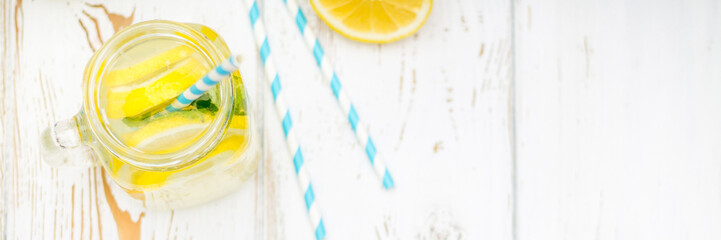 Banks with handles with cold lemonade on a white wooden background. Lemons. Top view. banner