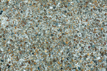 Pebble stone floor tile seamless background. Cement mixed gravel pebble stone floor texture. Wet round pebble stone rock floor in dramatic lighting.