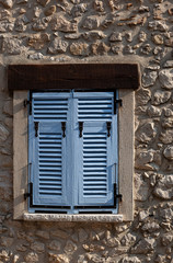 Fototapeta na wymiar Pastel blue shutters on a stone wall in Peille, France