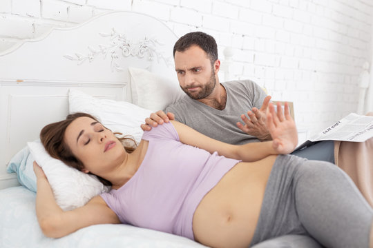 Wake up. Angry man waking up pregnant woman who sleeping