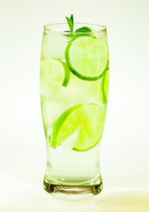 summer cold drink mojito lime and mint with ice and soda with drops on a glass on a white background
