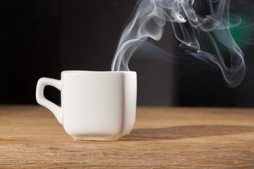 vapor  over a cup of morning breakfast on an oak table dark background