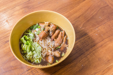 Bowl of chicken noodle soup with vegetables on wood table. Thai food.