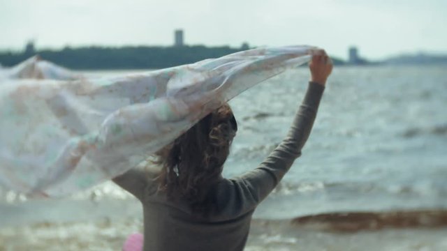A woman listens to music on headphones, relaxes and dances on the shore of the sea river of the ocean. Technology in the open air