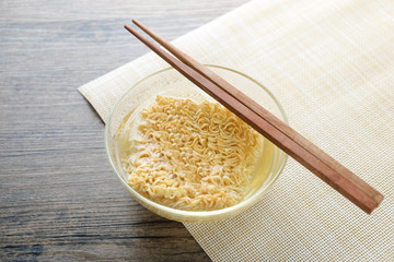 Glass bowl , chopsticks and instant noodle on the wooden table.