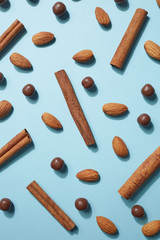 Fresh almonds, chocolate balls and cinnamon on a blue paper background, creative pattern. Flat lay