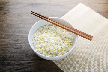 Bowl , chopsticks and instant noodle on the wooden table.