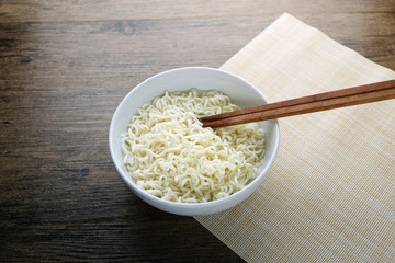 Bowl , chopsticks and instant noodle on the wooden table.