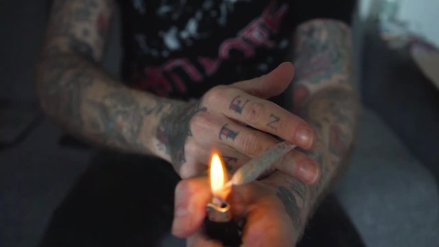 tattoed hand light joint Marijuana weed spliff junkey addiction legalise drugs