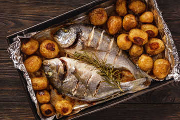 Baked dorado fish with potatoes.