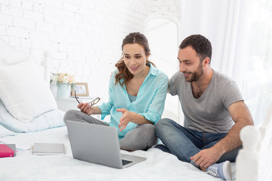 Lecture about baby. Appealing pregnant woman and man smiling and using laptop