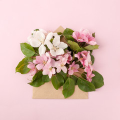 Festive flower apple tree composition and craft envelope on the pastel pink background. Overhead view