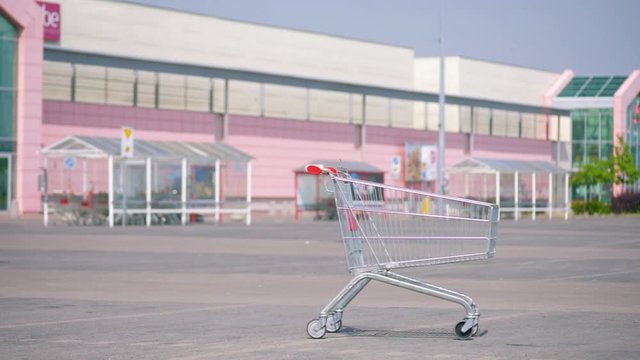 Pushing an empty shopping cart at parking. Shopping trolley in a parking lot near a supermarket. 