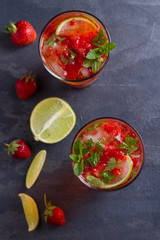 Strawberry mojito cocktail with berries, lime, mint and ice. Summer berry cocktail. View from above, top studio shot