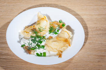 Ukrainian vareniki served on the Faror plate with onions, sour cream and dill