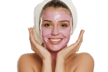 young smiling woman posing with  facial mask on her face with a towel on her head