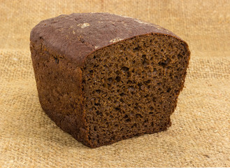 Partly cut brown rye and wheat bread on a sackcloth