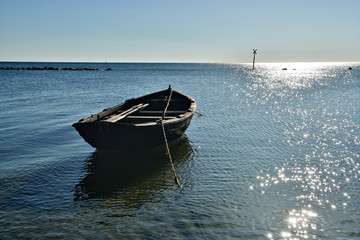 Kleines altes Fischerboot im glitzernden Wasser am Strand von Rügen