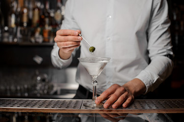 Fototapeta na wymiar Bartender adding an olive into the martini glass