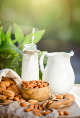 Almond and almond milk on a wooden table in the summer garden. Useful food.