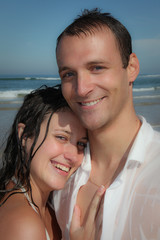 Beautiful young wet couple on the sandy beach of the sea