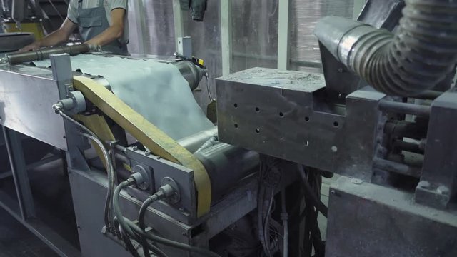 Production of powder paint, worker behind the machine, grinds hard material onto particles.
