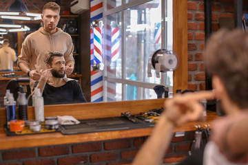 Professional barber working with client in hairdressing salon