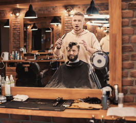 Professional barber working with client in hairdressing salon